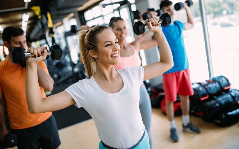 Athletic young woman doing a fitness workout with dumbbells in gym